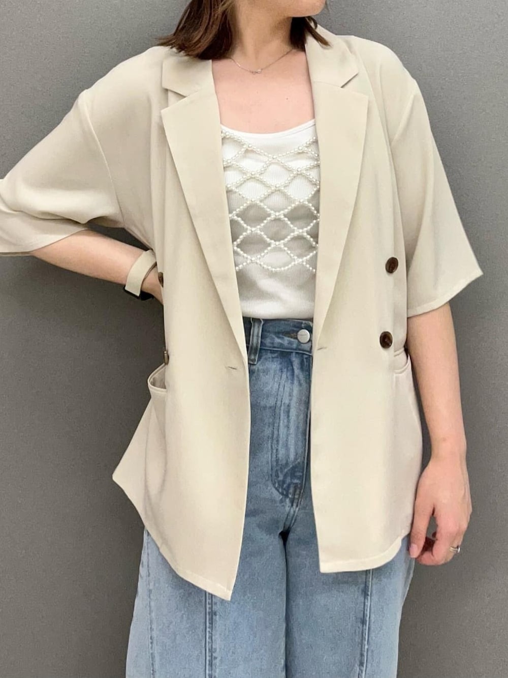 ベージュ系のベスト、ホワイト系のテーラードジャケット、ブルー系のデニムパンツを着用したレディースの夏コーディネートの2枚目の写真