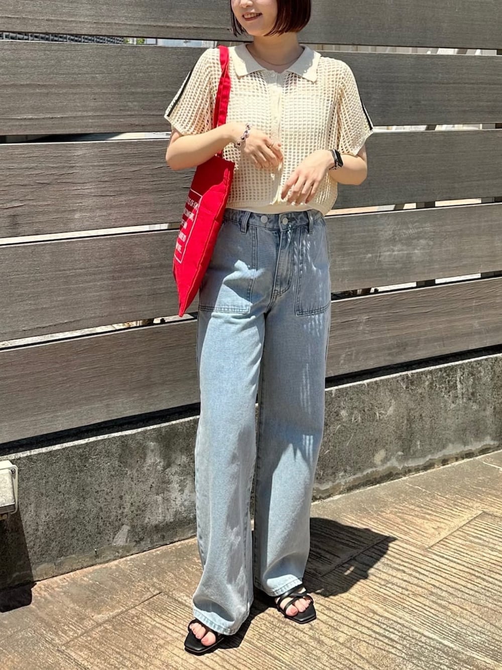 ホワイト系のニット/セーター、ホワイト系のデニムパンツ、レッド系のトートバッグを着用したレディースの夏コーディネートの2枚目の写真