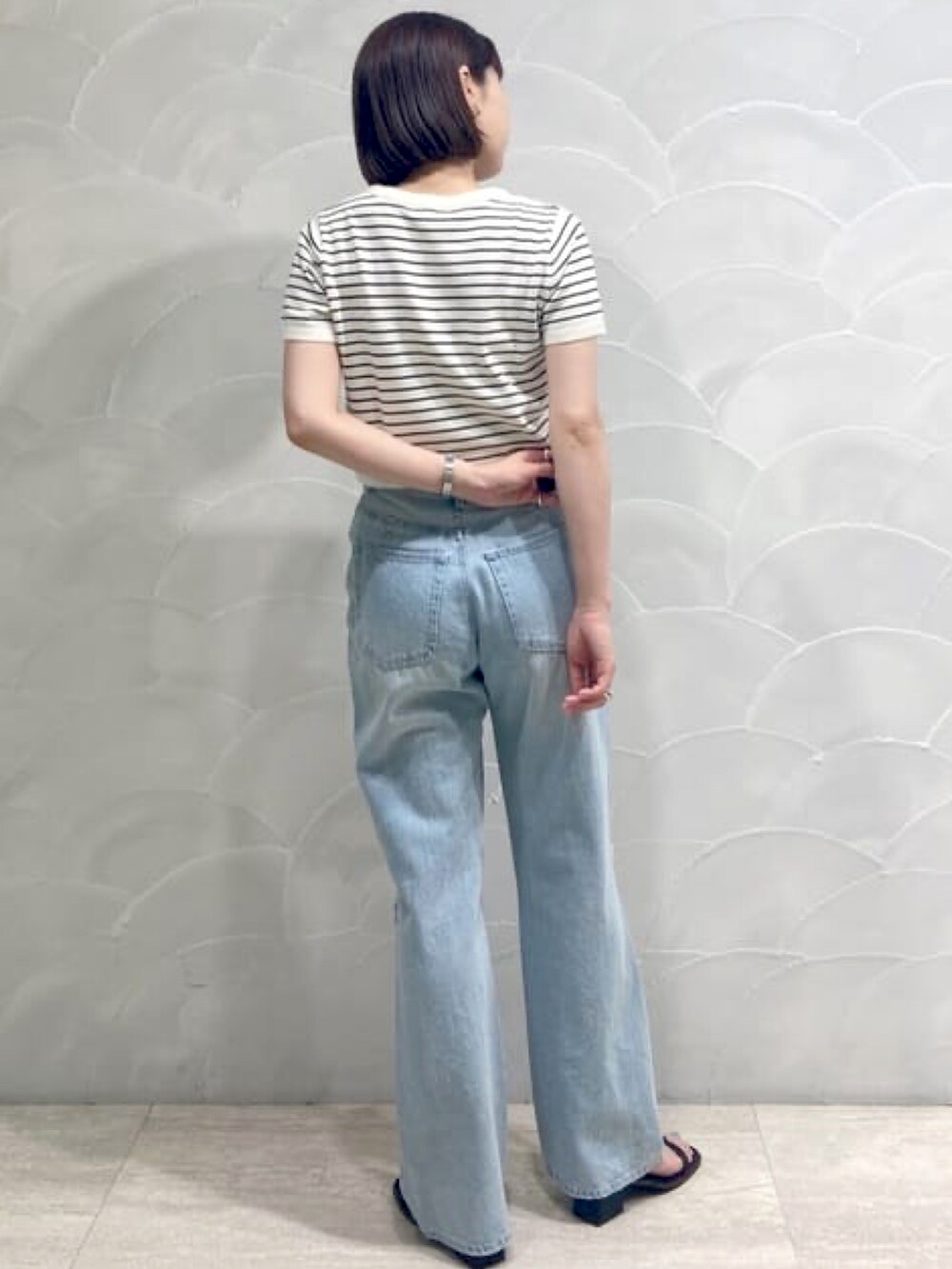 ホワイト系のニット/セーター、ブルー系のデニムパンツ、ブラック系のサンダルを着用したレディースの夏コーディネートの2枚目の写真