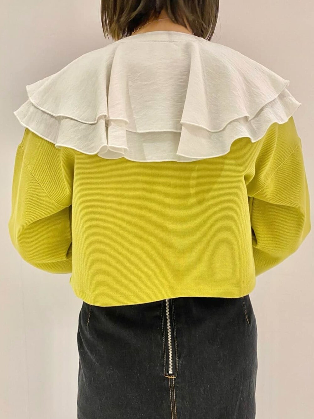 イエロー系のカーディガン/ボレロ、ブラック系のデニムスカート、ホワイト系のシャツ/ブラウスを着用したレディースの春コーディネートの3枚目の写真