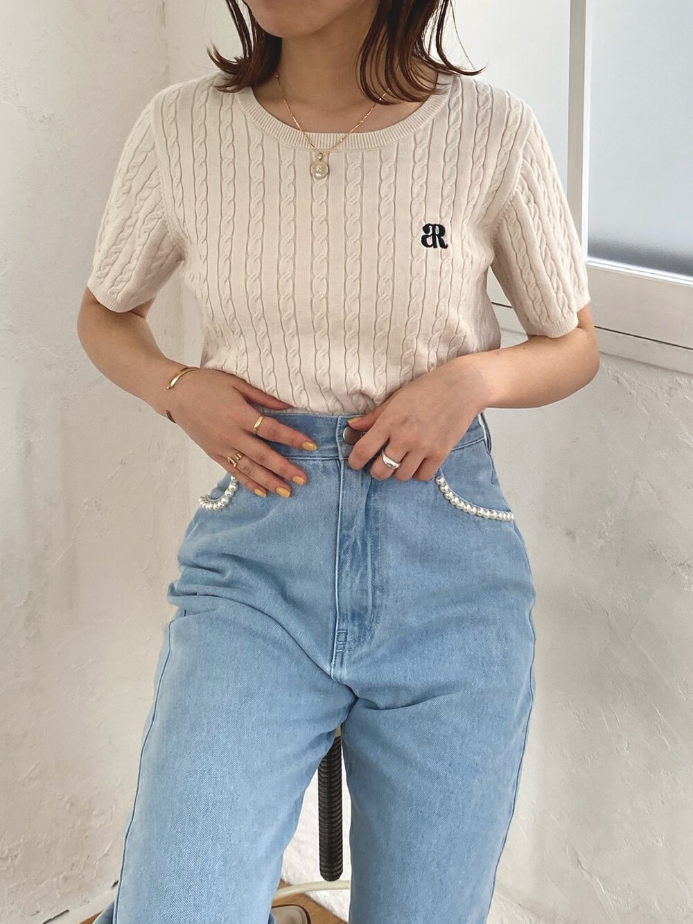 ホワイト系のニット/セーター、ブルー系のデニムパンツを着用したレディースの春コーディネートの2枚目の写真