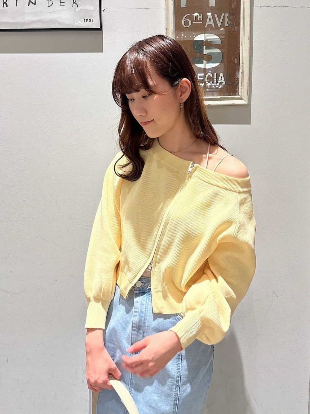 イエロー系のニット/セーター、ブルー系のデニムスカート、ホワイト系のショルダーバッグを着用したレディースの冬コーディネートの3枚目の写真