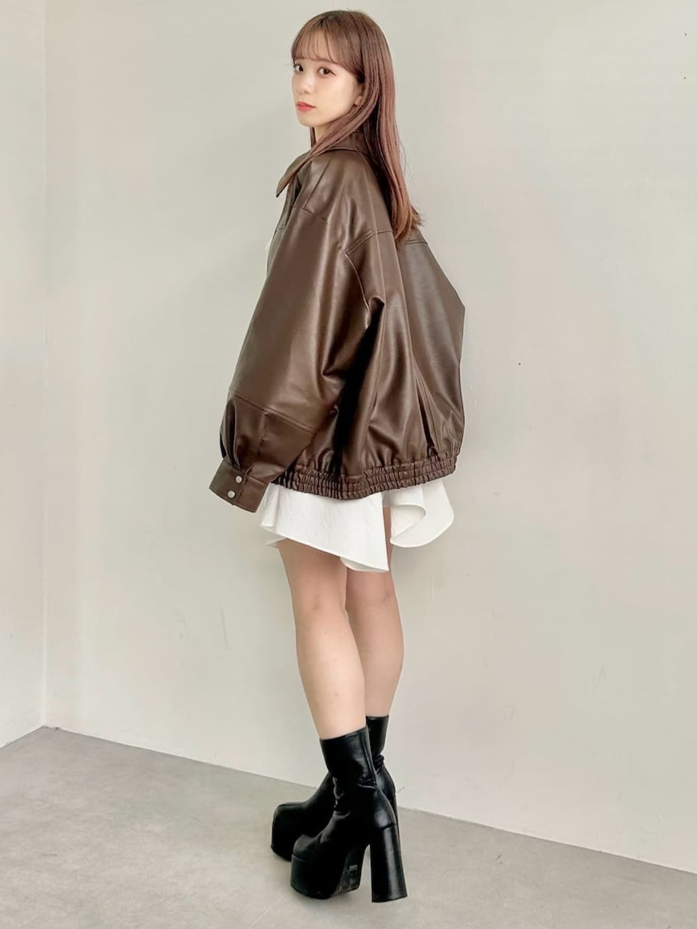 ブラウン系のブルゾン、ホワイト系のワンピースを着用したレディースの秋コーディネートの2枚目の写真