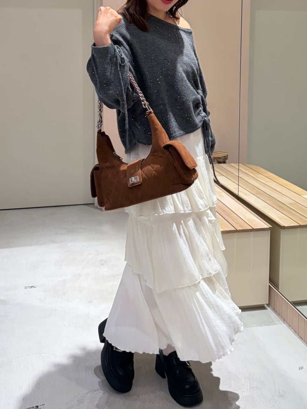 グレー系のニット/セーター、ホワイト系のスカート、ブラウン系のショルダーバッグを着用したレディースの秋コーディネートの2枚目の写真