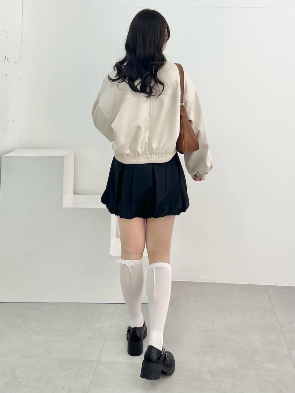 ホワイト系のブルゾン、ホワイト系のニット/セーター、ブラック系のスカートを着用したレディースの春コーディネートの2枚目の写真