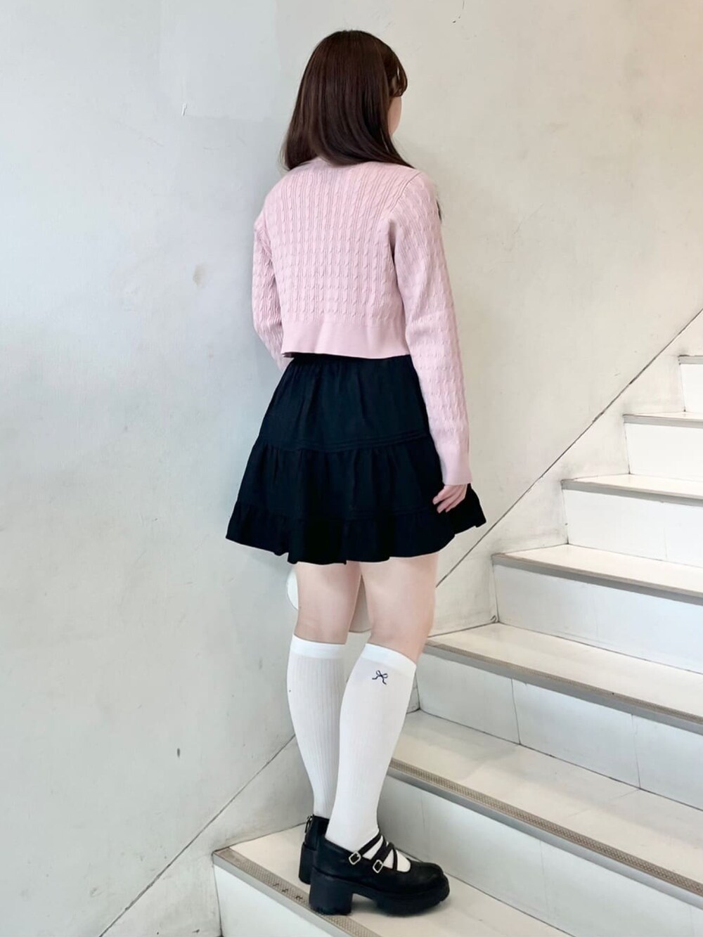 ピンク系のニット/セーター、ブラック系のスカート、ブラック系のパンプスを着用したレディースの冬コーディネートの2枚目の写真