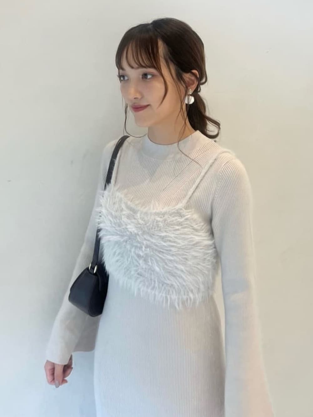 ホワイト系のワンピース、ブラウン系のショルダーバッグ、ホワイト系のブーツを着用したレディースの冬コーディネートの3枚目の写真