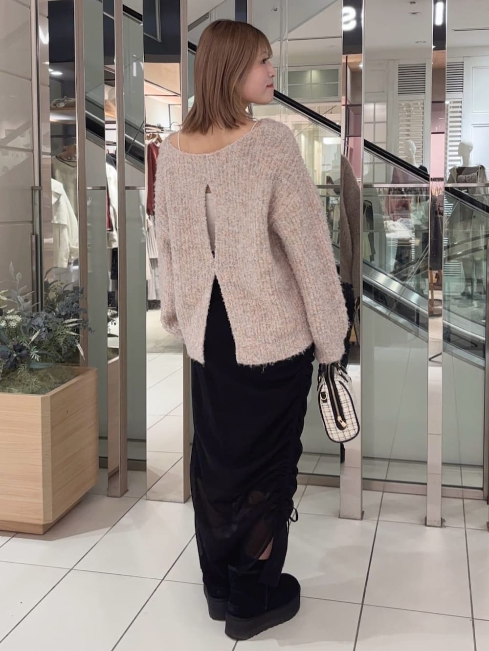 ピンク系のニット/セーター、ブラック系のスカート、ホワイト系のボストンバッグを着用したレディースの冬コーディネートの2枚目の写真