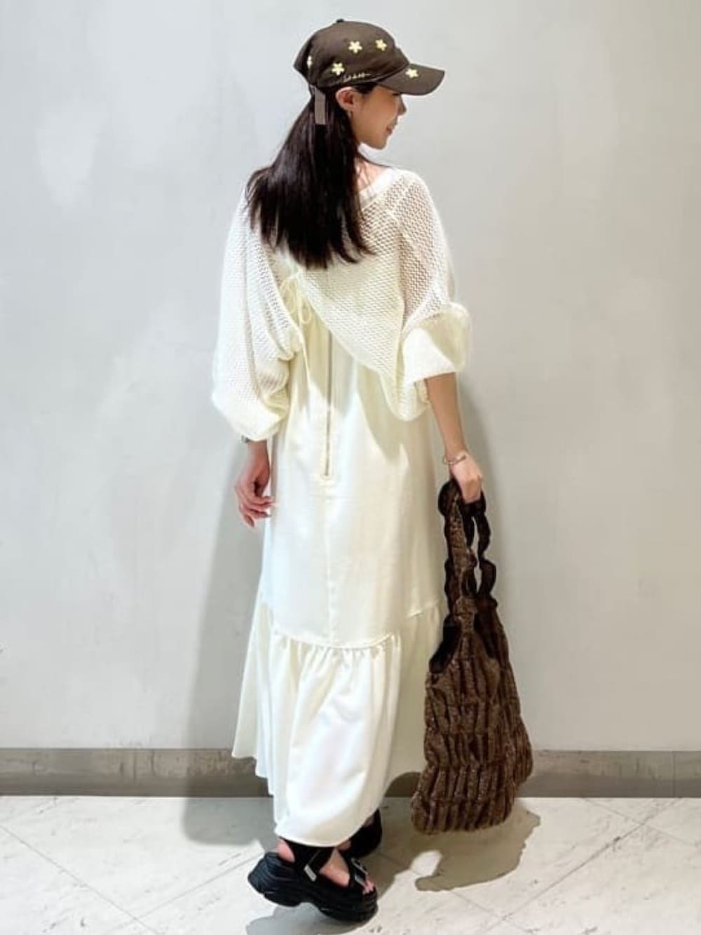 ブラック系のサンダル、ホワイト系のワンピース、ブラウン系のトートバッグを着用したレディースの夏コーディネートの2枚目の写真