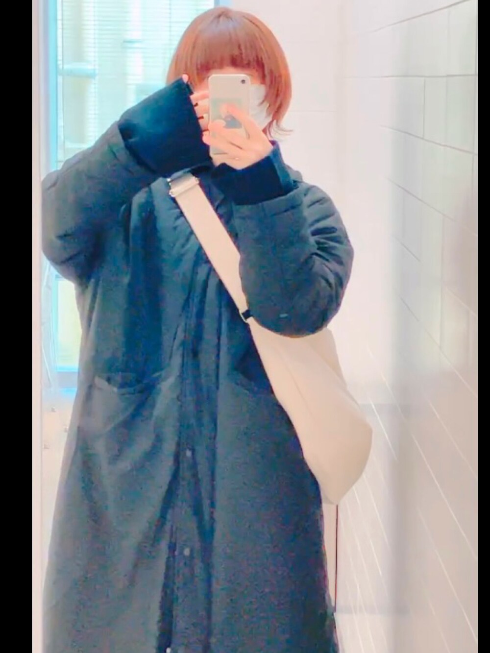 ホワイト系のショルダーバッグを着用したレディースの冬コーディネートの2枚目の写真