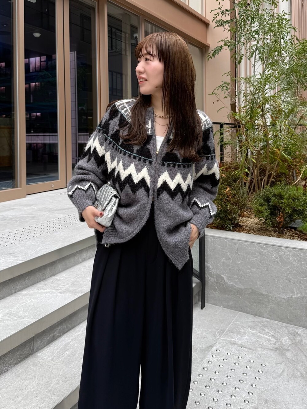 ブラック系のスラックス、グレー系のカーディガン/ボレロ、シルバー系のショルダーバッグを着用したレディースの秋コーディネートの5枚目の写真