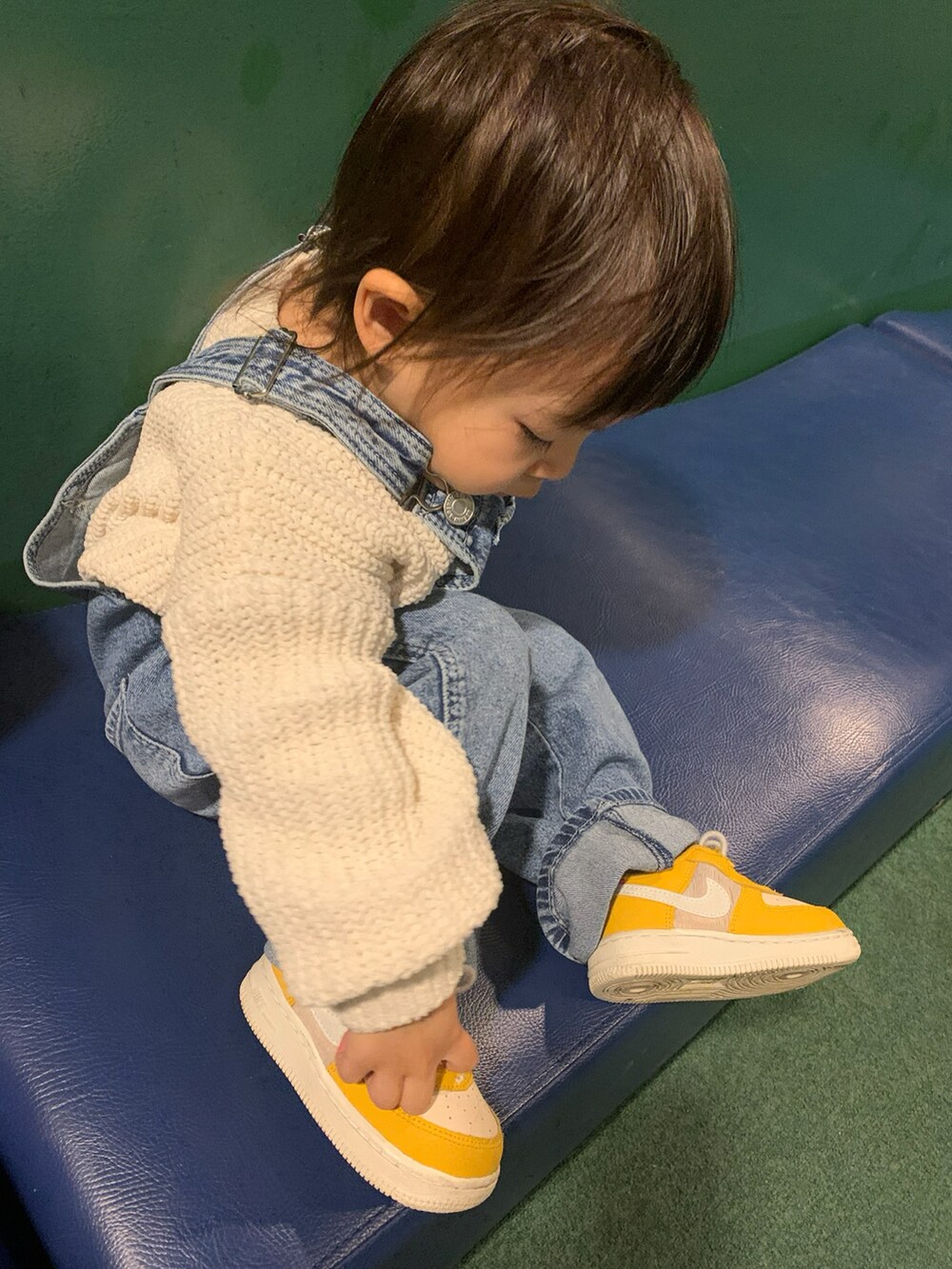 ホワイト系のニット/セーター、ブルー系のサロペット/オーバーオール、イエロー系のスニーカーを着用したキッズの冬コーディネートの2枚目の写真