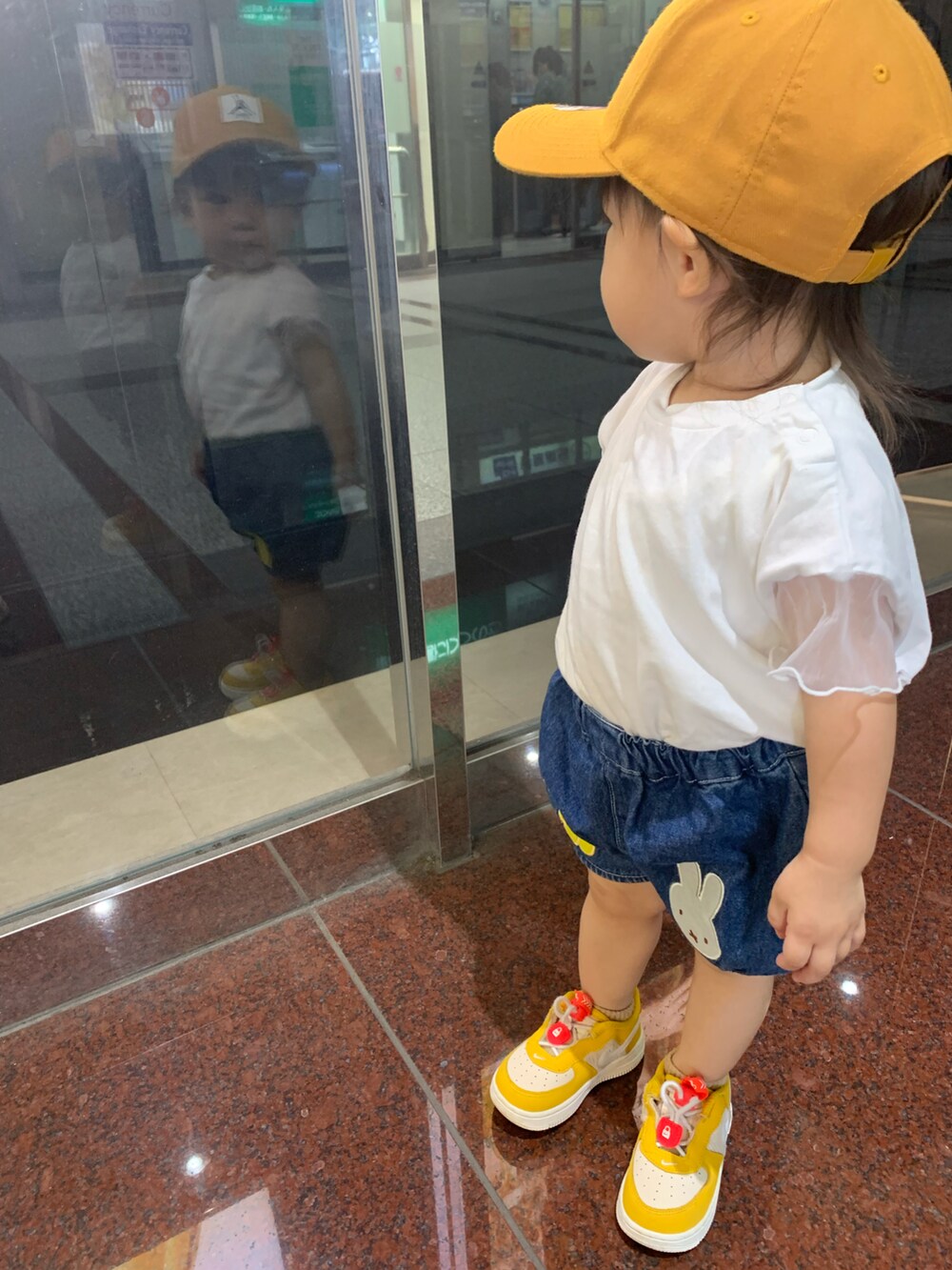 ホワイト系のトップス、イエロー系のスニーカー、ブルー系のデニムパンツを着用したキッズの秋コーディネートの2枚目の写真
