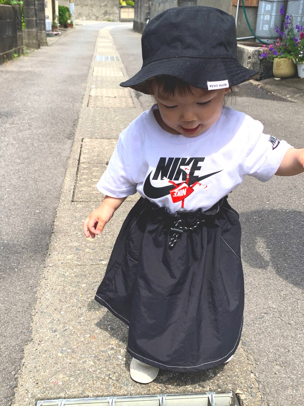 ホワイト系のTシャツ/カットソー、ブラック系のスカート、ブラック系のハットを着用したキッズの春コーディネートの2枚目の写真