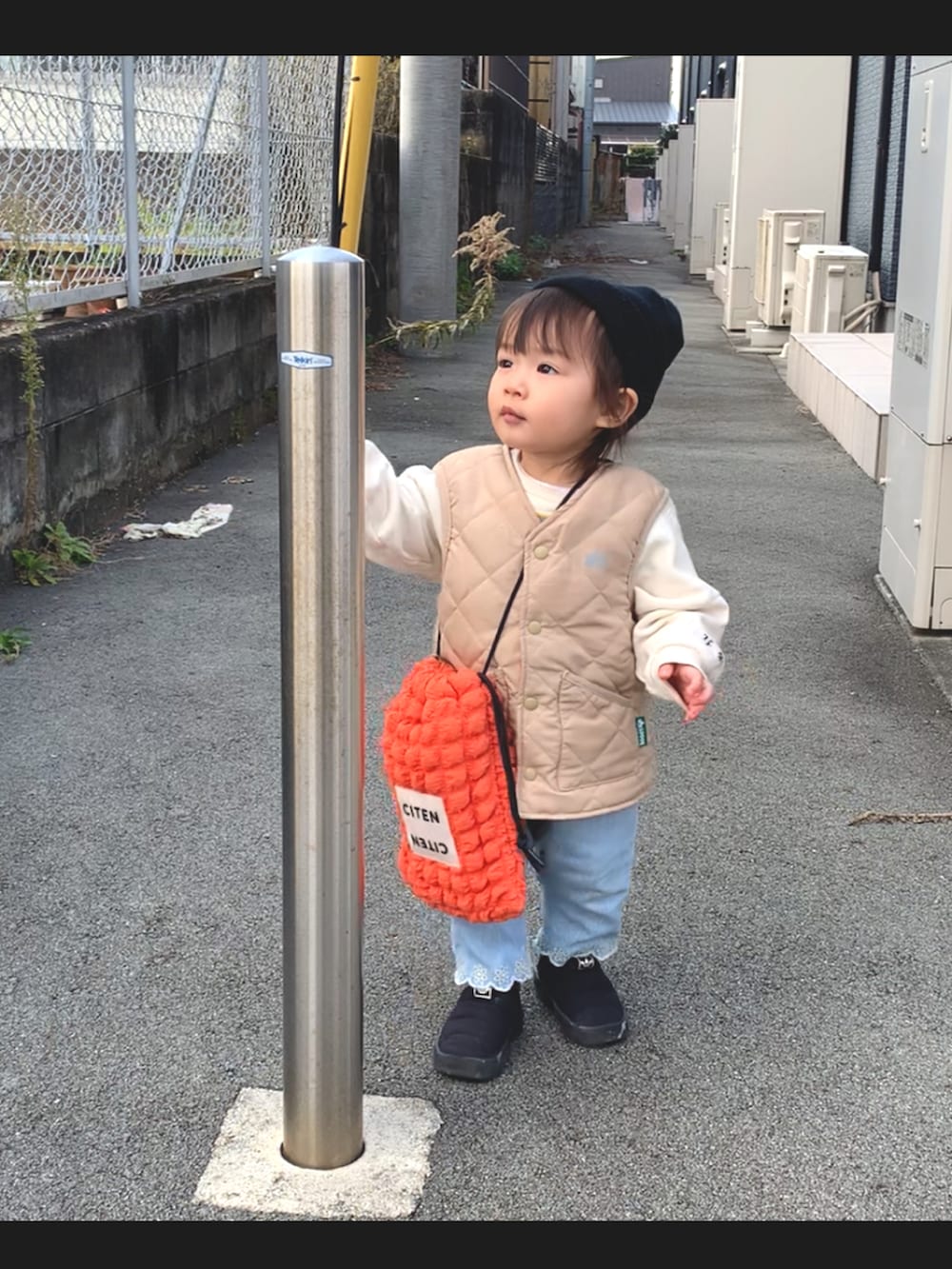 オレンジ系のショルダーバッグ、ブラック系のその他シューズ、ブルー系のデニムパンツを着用したキッズの冬コーディネートの2枚目の写真
