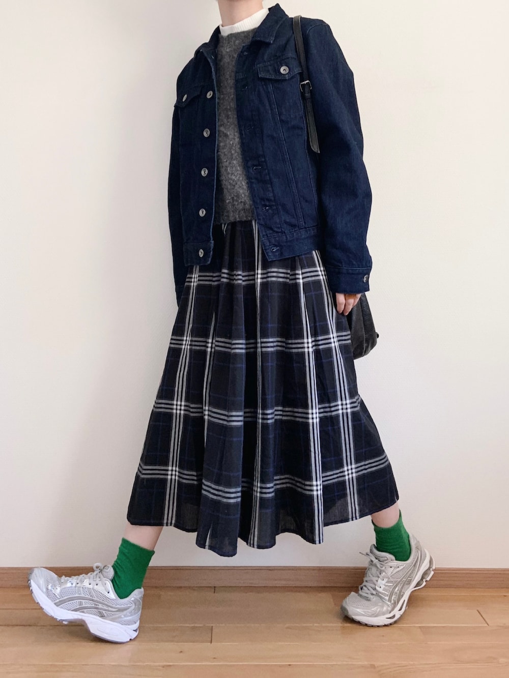 グレー系のベスト、ホワイト系のニット/セーター、ブルー系のスカートを着用したレディースの春コーディネートの2枚目の写真