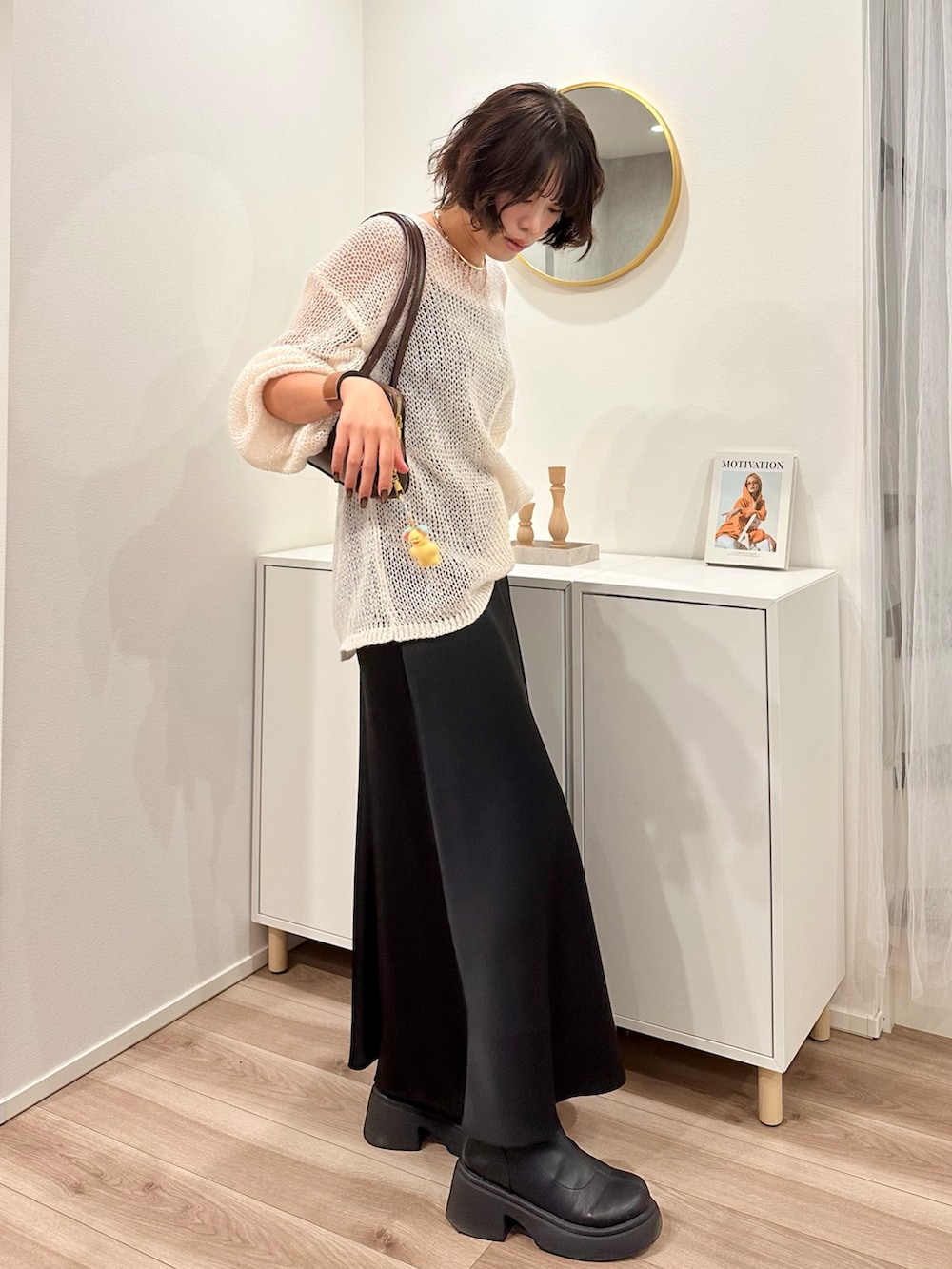 ホワイト系のニット/セーター、ブラウン系のボストンバッグ、ブラック系のスカートを着用したレディースの秋コーディネートの3枚目の写真
