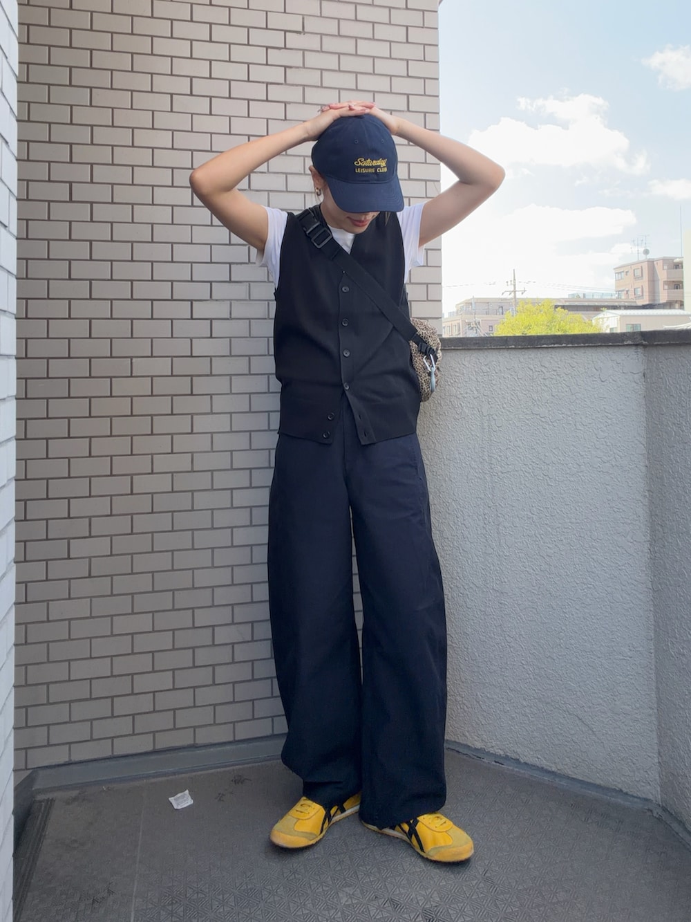 イエロー系のスニーカー、ブラック系のその他パンツ、ブラック系のベストを着用したレディースの春コーディネートの4枚目の写真