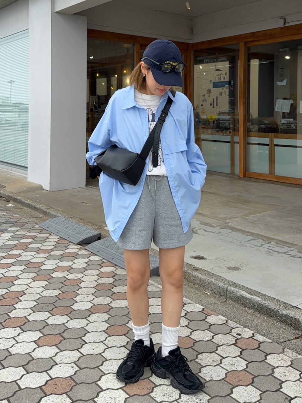 ブラック系のショルダーバッグ、ホワイト系のTシャツ/カットソー、ブラック系のスニーカーを着用したレディースの夏コーディネートの2枚目の写真