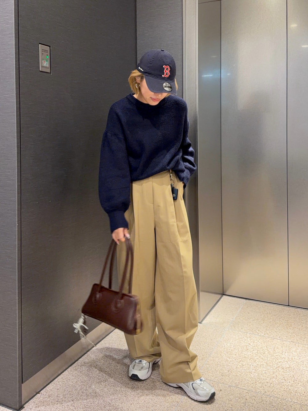 ベージュ系のスラックス、ブラウン系のボストンバッグ、ホワイト系のスニーカーを着用したレディースの冬コーディネートの2枚目の写真