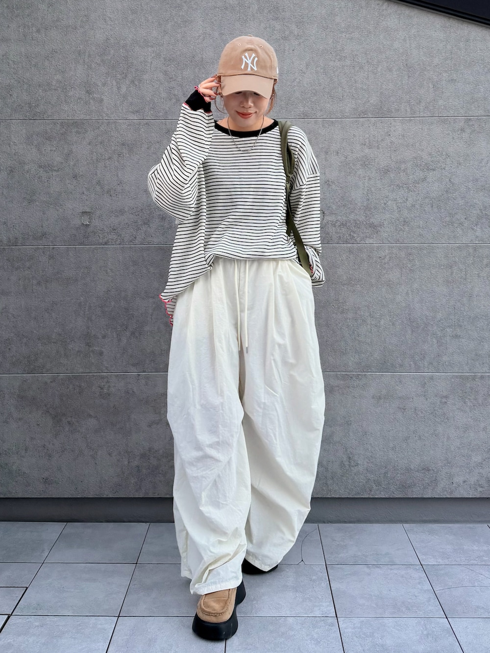 ホワイト系のTシャツ/カットソー、グリーン系のバックパック/リュック、ベージュ系のサンダルを着用したレディースの秋コーディネートの2枚目の写真