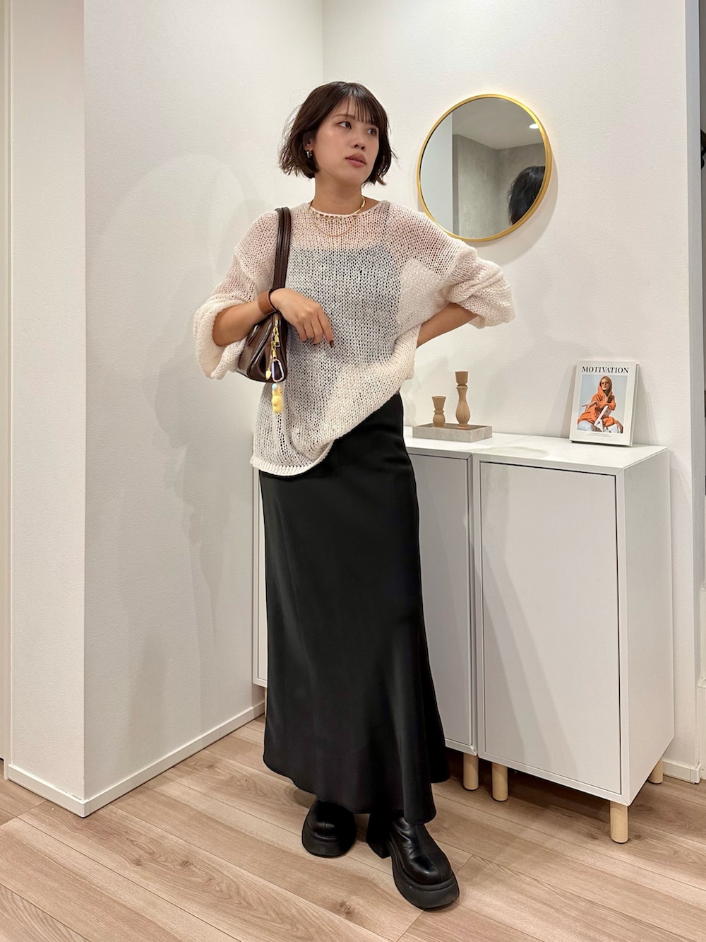 ホワイト系のニット/セーター、ブラウン系のボストンバッグ、ブラック系のスカートを着用したレディースの秋コーディネートの2枚目の写真
