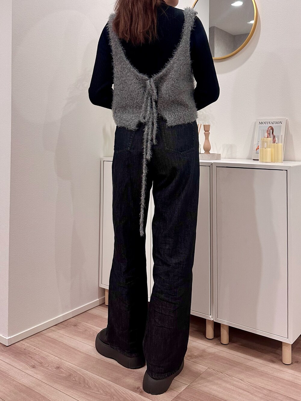 ブラック系のデニムパンツ、ブラック系のサンダル、シルバー系のボストンバッグを着用したレディースの冬コーディネートの2枚目の写真