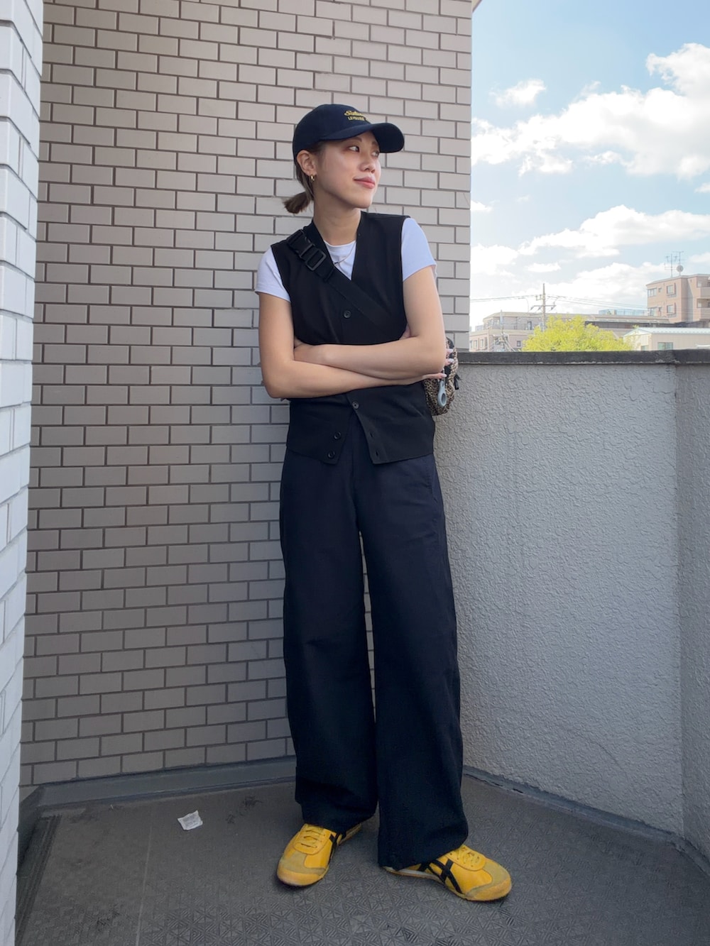イエロー系のスニーカー、ブラック系のその他パンツ、ブラック系のベストを着用したレディースの春コーディネートの3枚目の写真