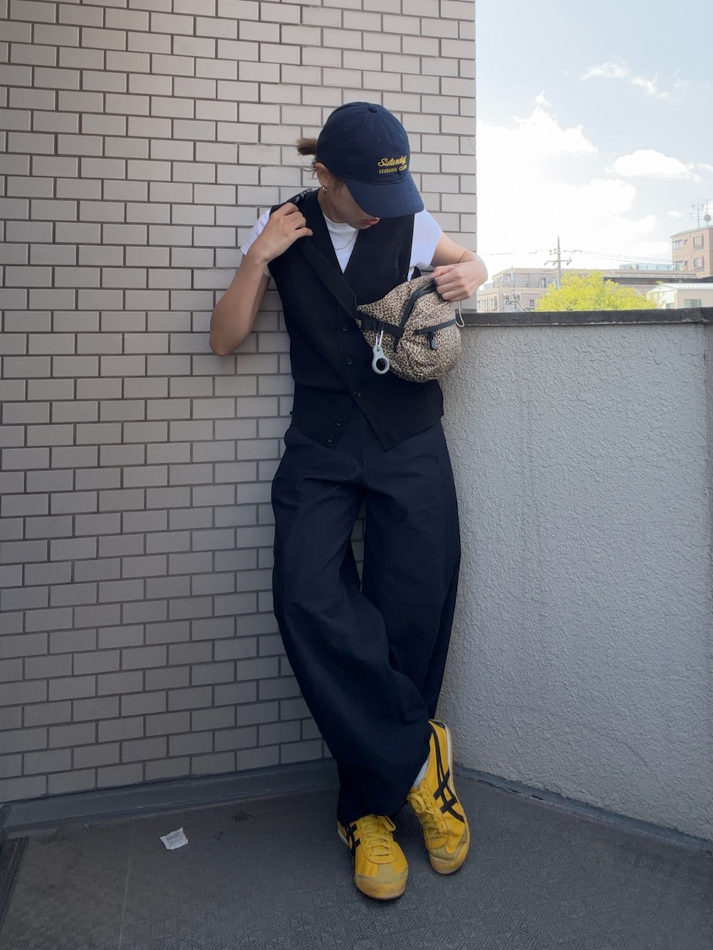 イエロー系のスニーカー、ブラック系のその他パンツ、ブラック系のベストを着用したレディースの春コーディネートの2枚目の写真