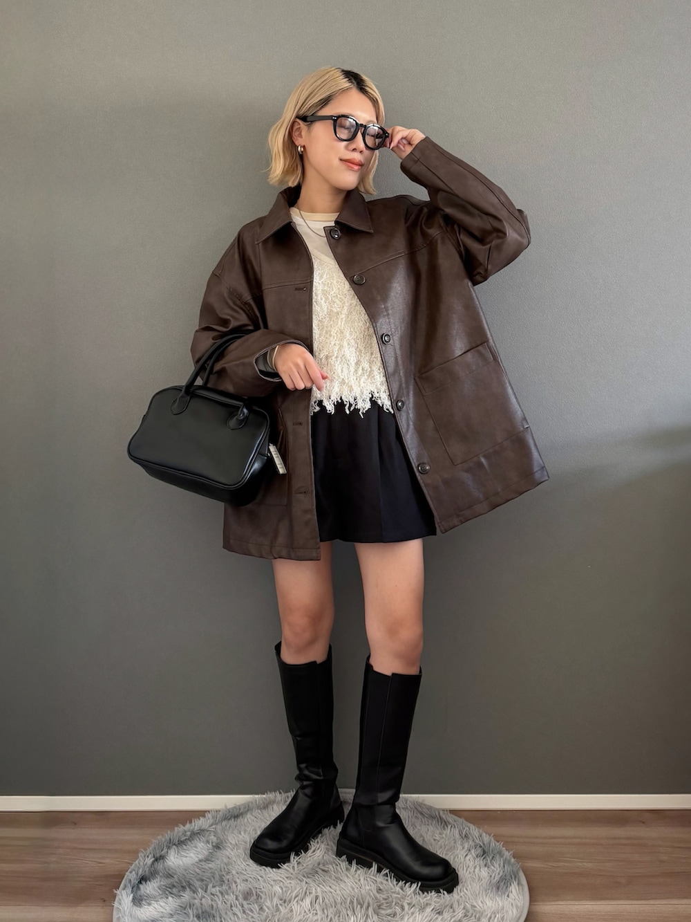 ブラウン系のステンカラーコート、ホワイト系のベスト、ブラック系のその他パンツを着用したレディースの春コーディネートの2枚目の写真