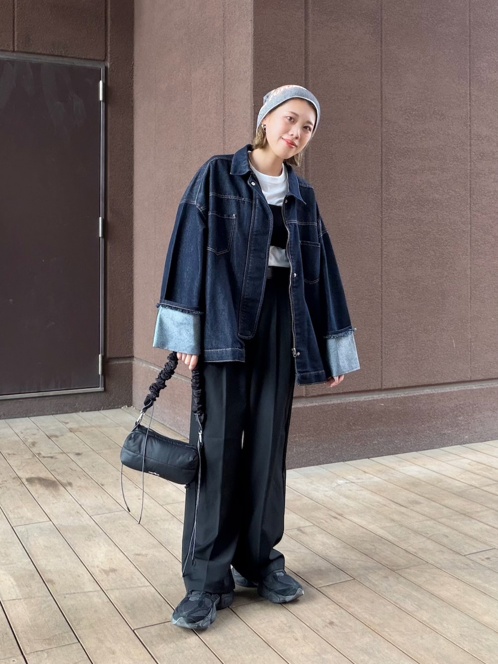 ブラック系のスラックス、ブラック系のスニーカー、ブルー系のデニムジャケットを着用したレディースの春コーディネートの3枚目の写真