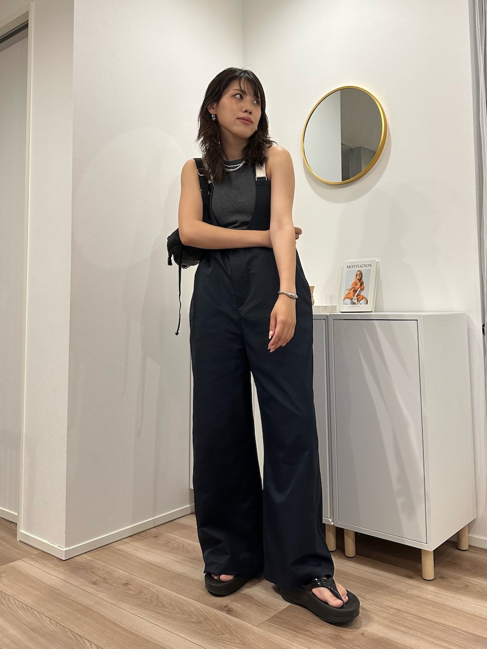 グレー系のタンクトップ、ブルー系のサロペット/オーバーオール、ブラック系のサンダルを着用したレディースの夏コーディネートの2枚目の写真