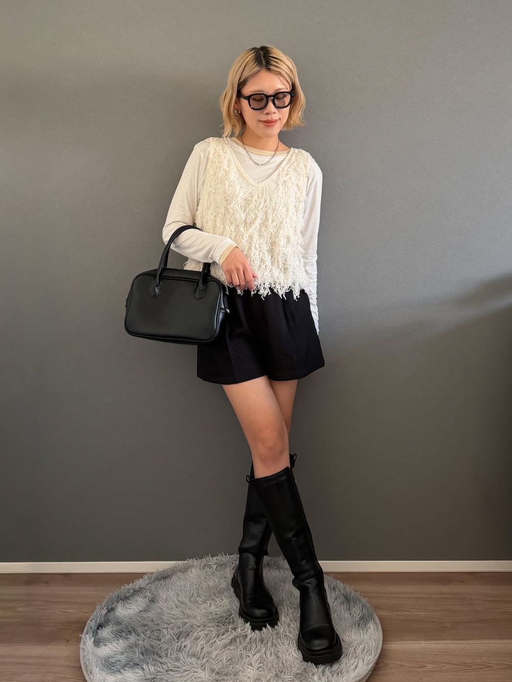 ブラウン系のステンカラーコート、ホワイト系のベスト、ブラック系のその他パンツを着用したレディースの春コーディネートの3枚目の写真