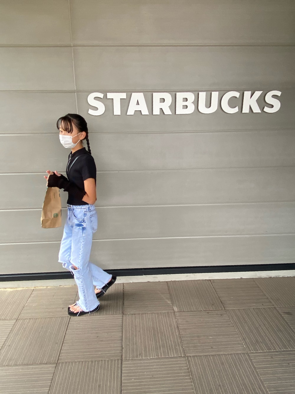 ブラック系のTシャツ/カットソー、ブルー系のデニムパンツ、ブラック系のサンダルを着用したキッズの秋コーディネートの2枚目の写真