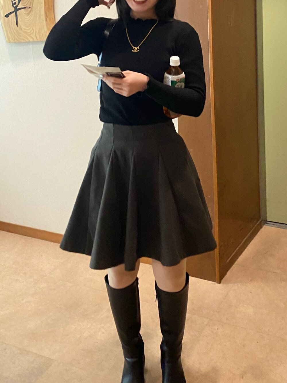 ブラック系のハンドバッグ、ブラック系のブーツ、グレー系のスカートを着用したレディースの冬コーディネートの2枚目の写真