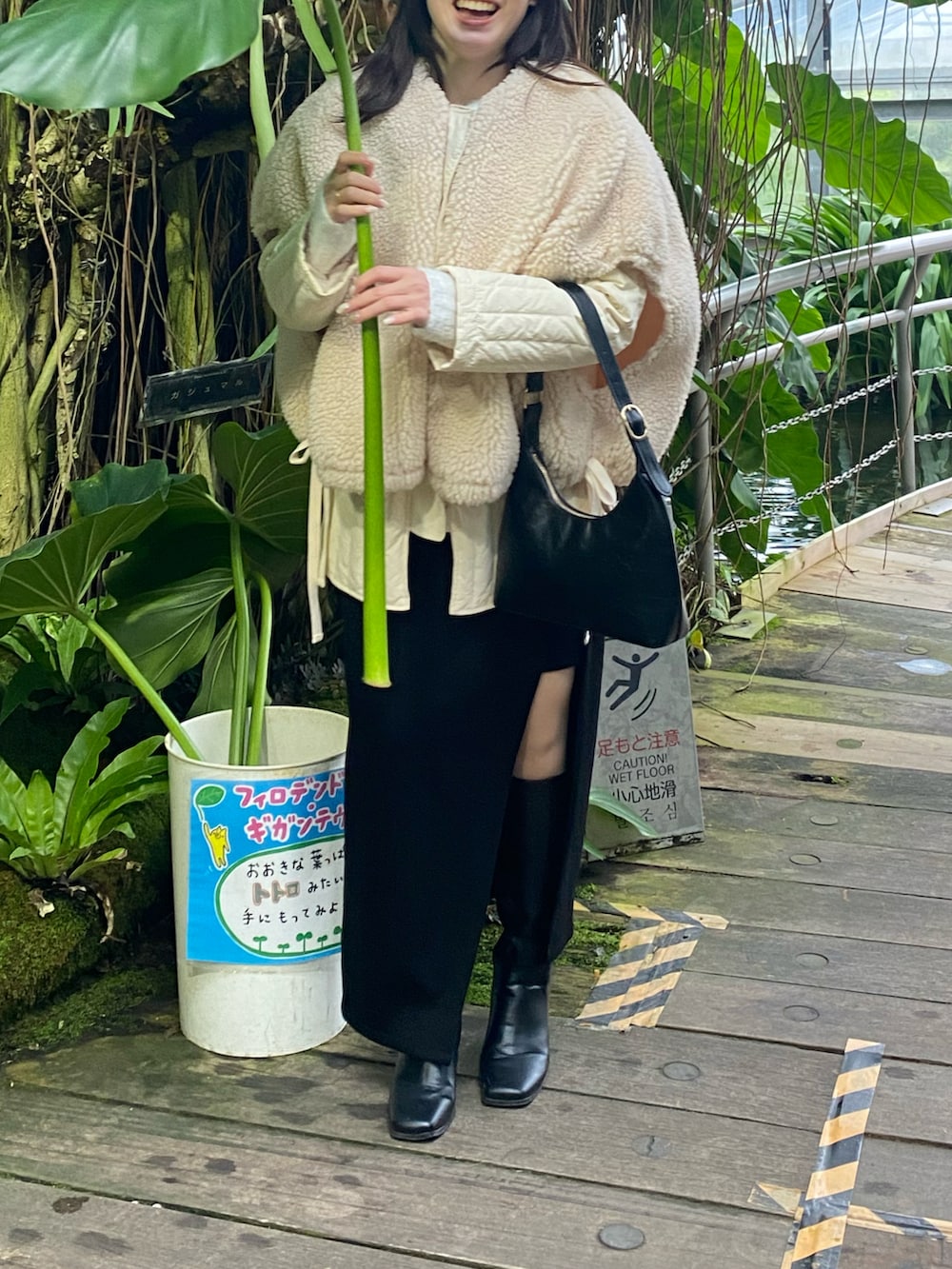 ブラック系のハンドバッグ、ブラック系のスカート、ブラック系のブーツを着用したレディースの冬コーディネートの2枚目の写真