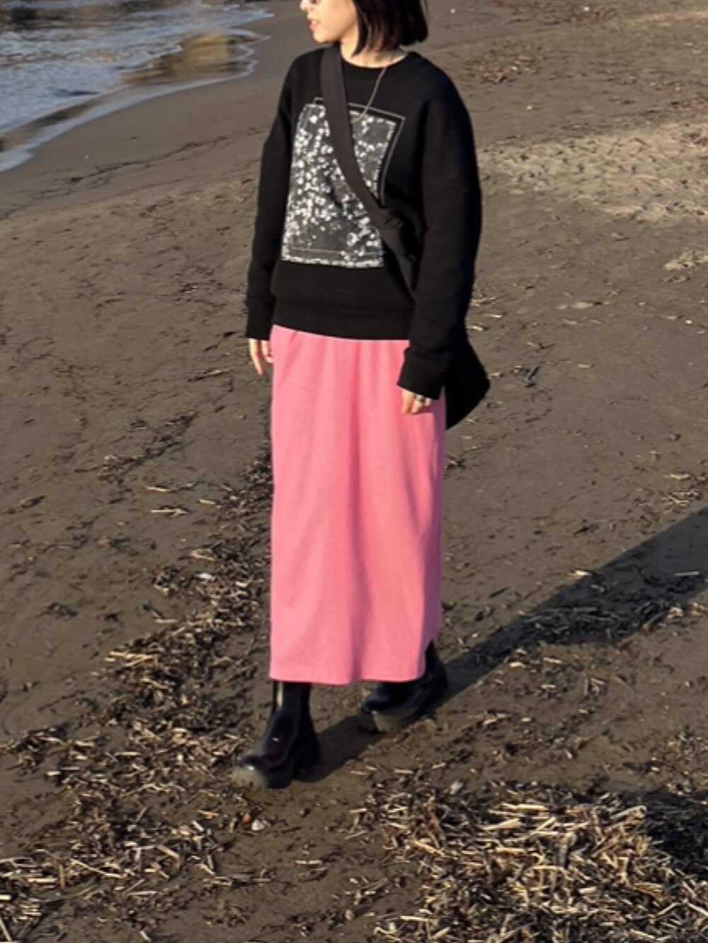 ピンク系のスカート、ブラック系のスウェット、ブラック系のブーツを着用したレディースの冬コーディネートの2枚目の写真