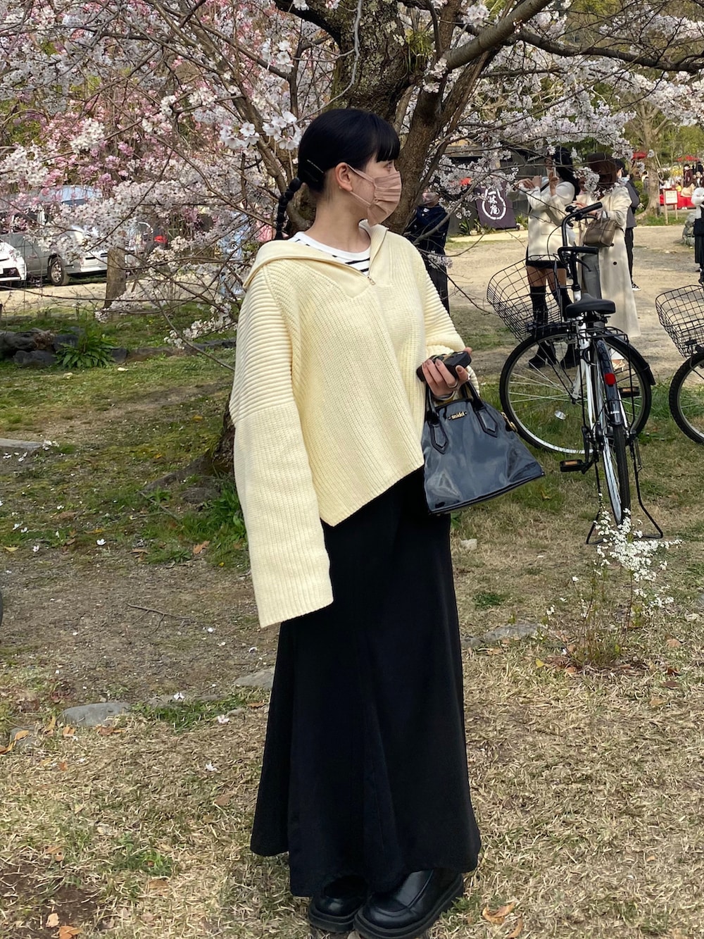 ブラック系のバッグ、ブラック系のスカート、ホワイト系のニット/セーターを着用したレディースの春コーディネートの2枚目の写真