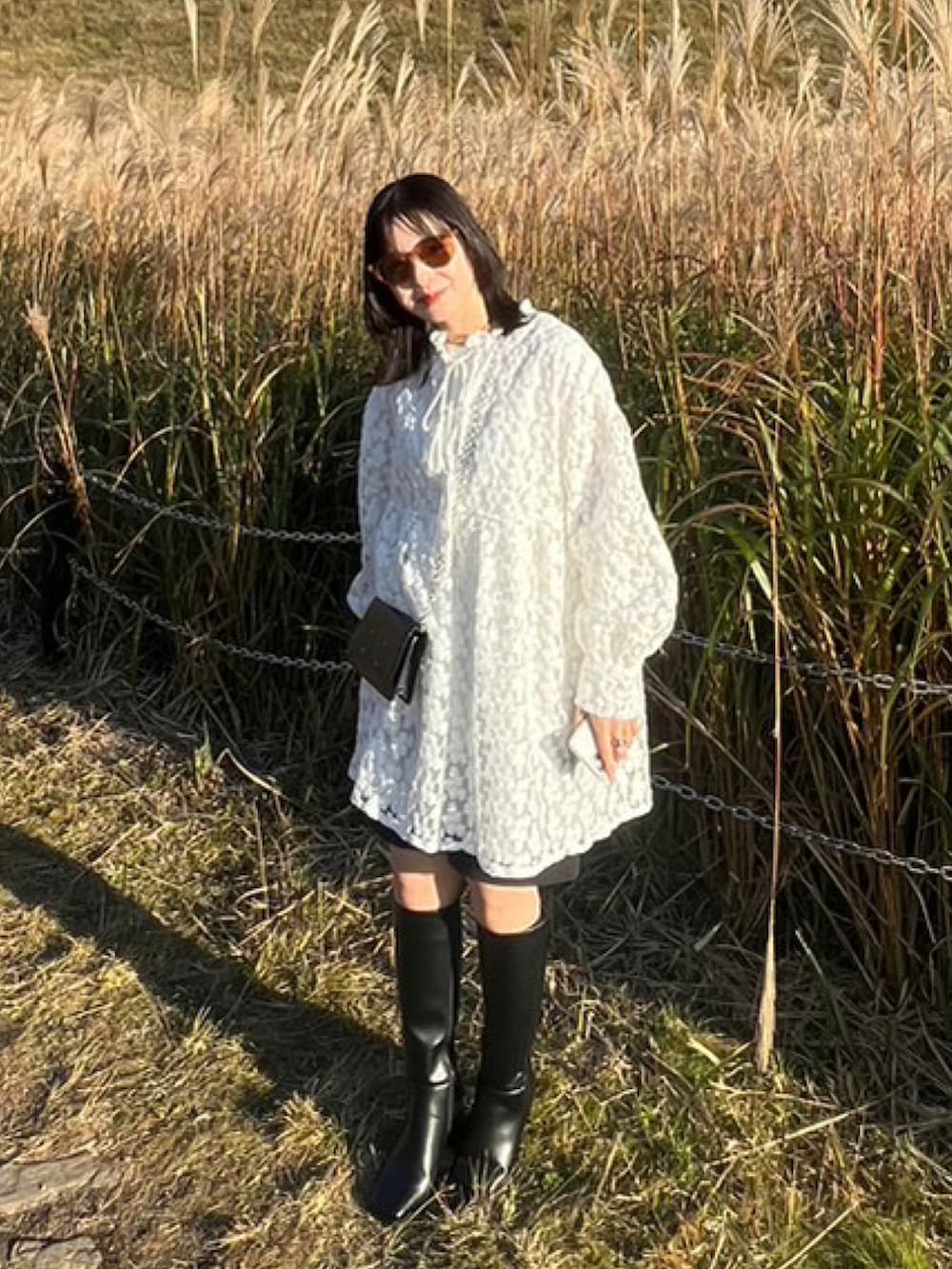 ブラック系のブーツ、ホワイト系のワンピース/ドレス、ブラック系のバッグを着用したレディースの秋コーディネートの2枚目の写真