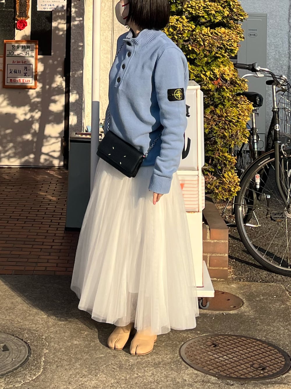 ホワイト系のスカート、ベージュ系のブーツ、ブラック系のバッグを着用したレディースの冬コーディネートの2枚目の写真