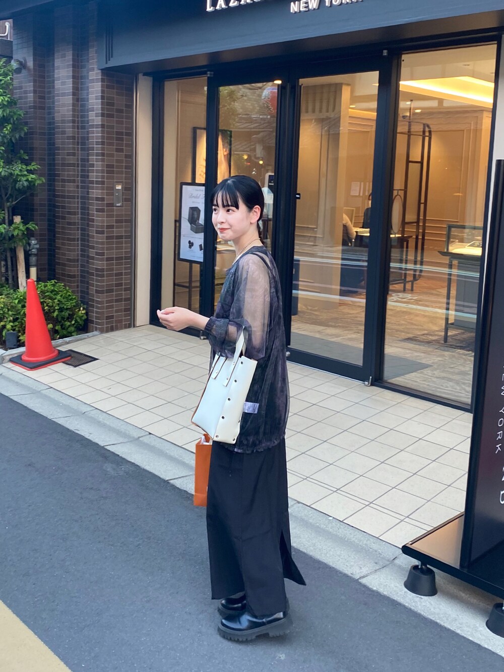 ブラック系のワンピース、パープル系のトップス、ホワイト系のハンドバッグを着用したレディースの夏コーディネートの2枚目の写真