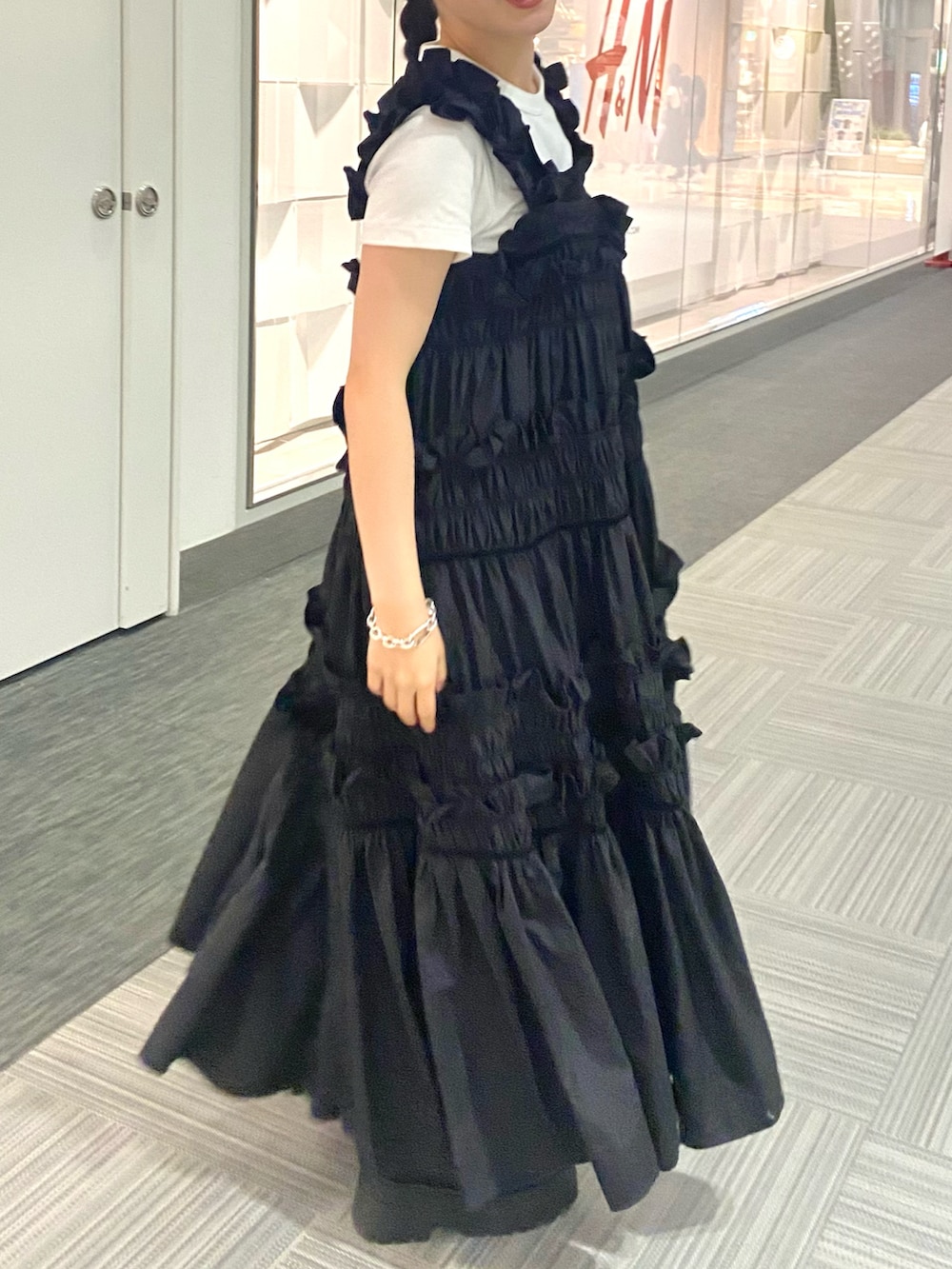 ホワイト系のハンドバッグ、ブラック系のワンピース、ブラック系のブーツを着用したレディースの夏コーディネートの2枚目の写真