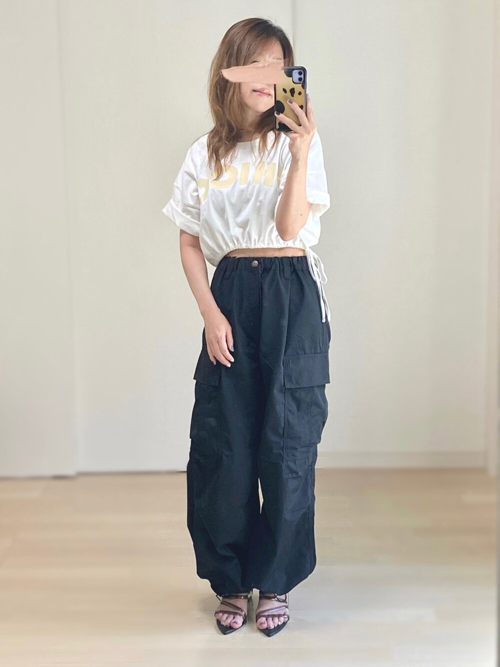 ブラック系のカーゴパンツ、ホワイト系のTシャツ/カットソー、ブラック系のサンダルを着用したレディースの夏コーディネートの3枚目の写真