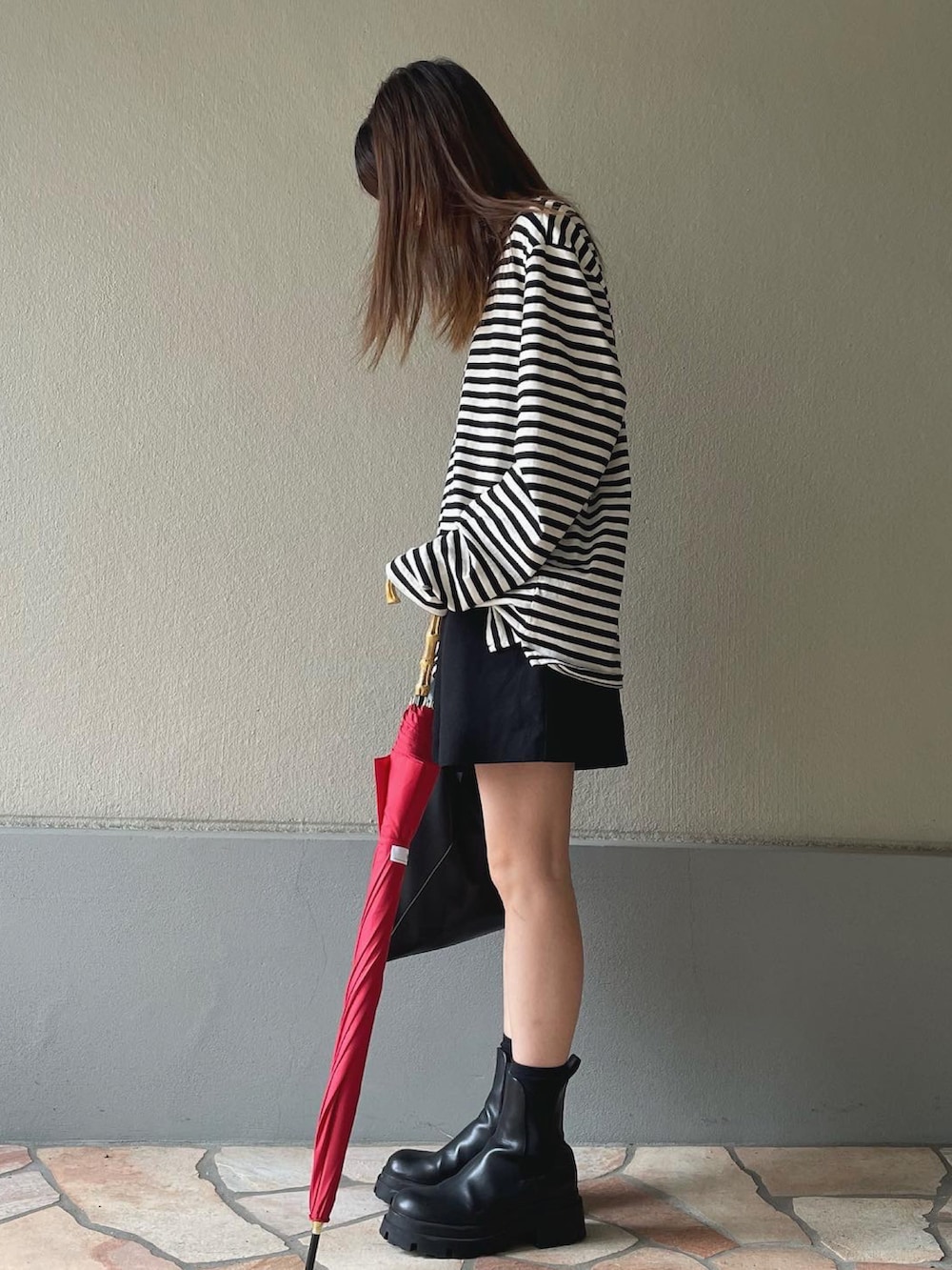 ブラック系のハンドバッグ、レッド系の長傘を着用したレディースの秋コーディネートの2枚目の写真