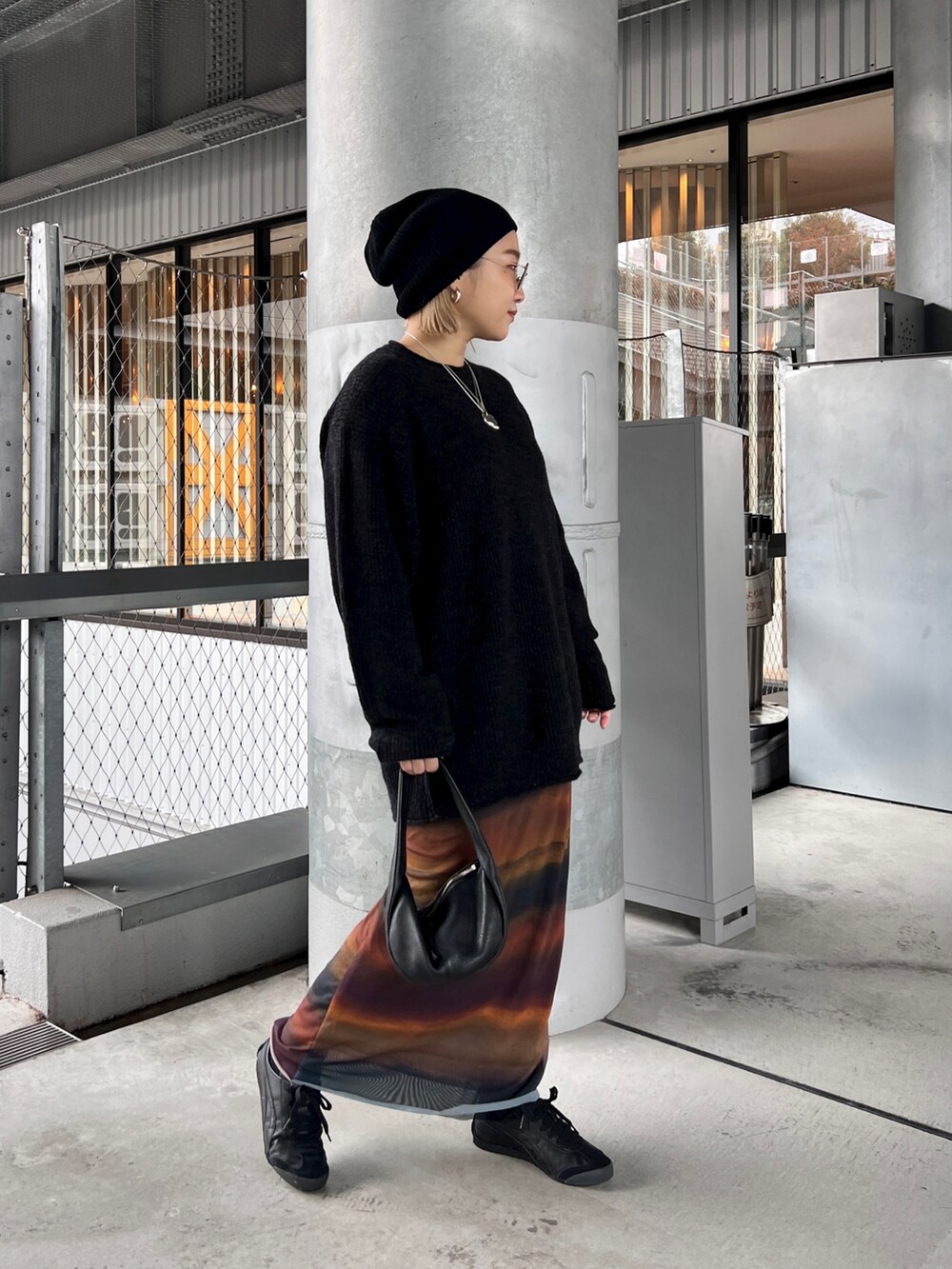 ブラック系のハンドバッグ、ブラック系のスニーカー、ブラック系のニットキャップ/ビーニーを着用したレディースの冬コーディネートの2枚目の写真