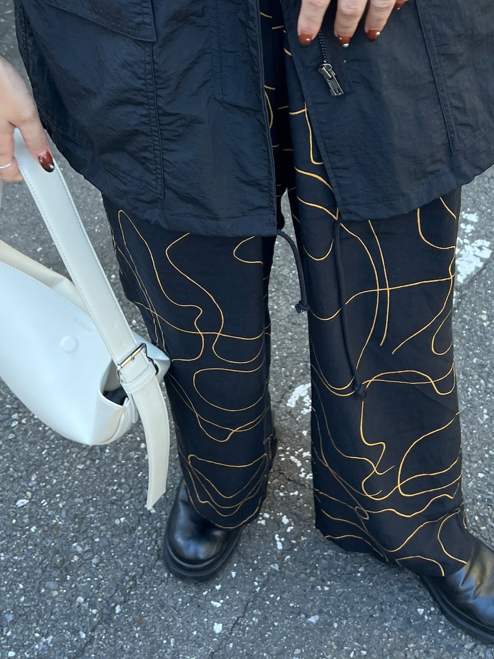 ホワイト系のショルダーバッグ、ブラック系のジャケット/アウター、ブラック系のスラックスを着用したレディースの秋コーディネートの3枚目の写真