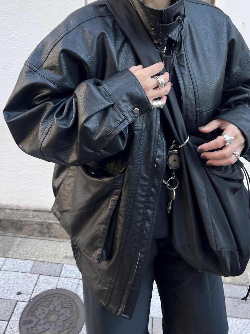 ブラック系のショルダーバッグ、ブラック系のライダースジャケット、ブラック系のスニーカーを着用したレディースの冬コーディネートの2枚目の写真