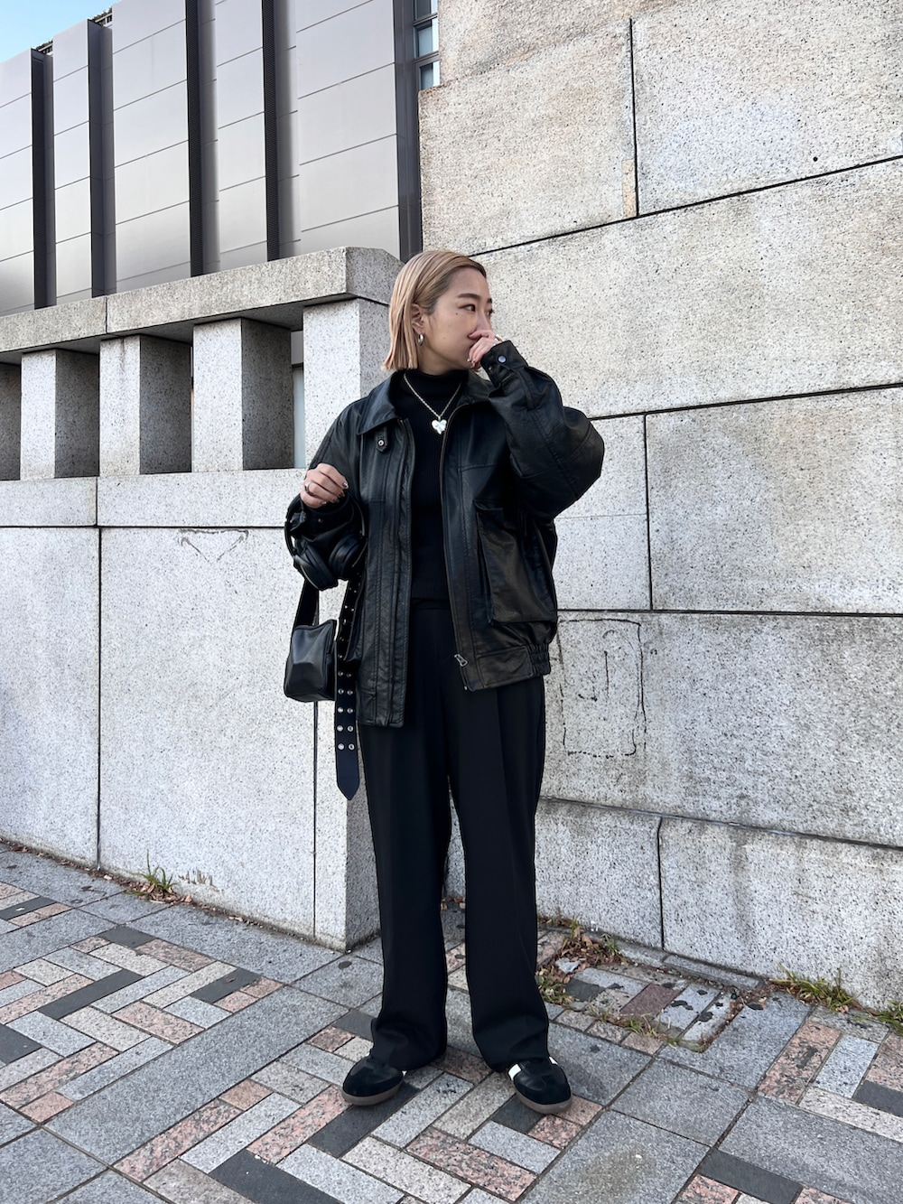 ブラック系のスニーカー、ブラック系のショルダーバッグ、ブラック系のライダースジャケットを着用したレディースの冬コーディネートの2枚目の写真