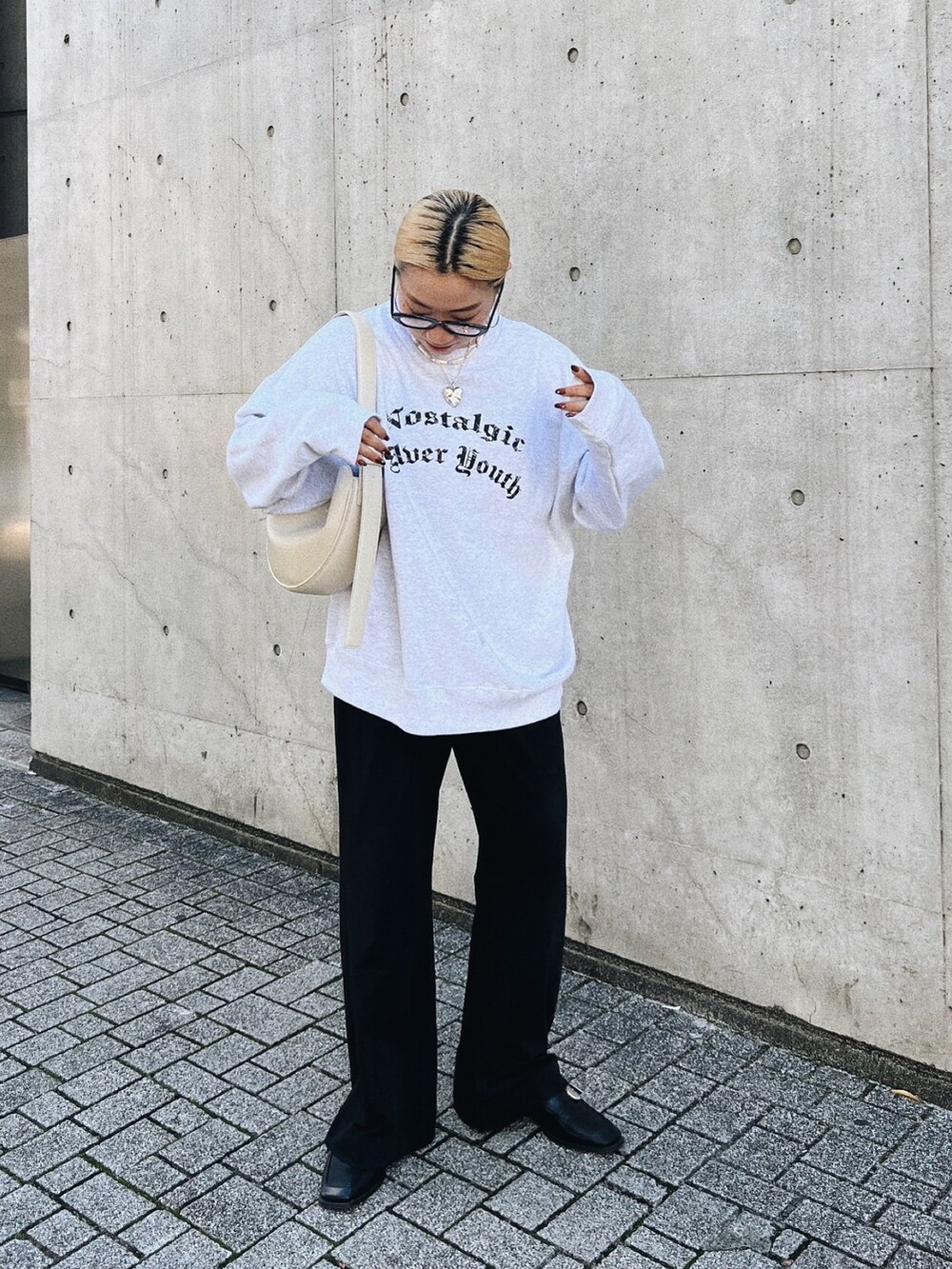 ブラック系のパンツ、グレー系のスウェット、ホワイト系のショルダーバッグを着用したレディースの秋コーディネートの2枚目の写真