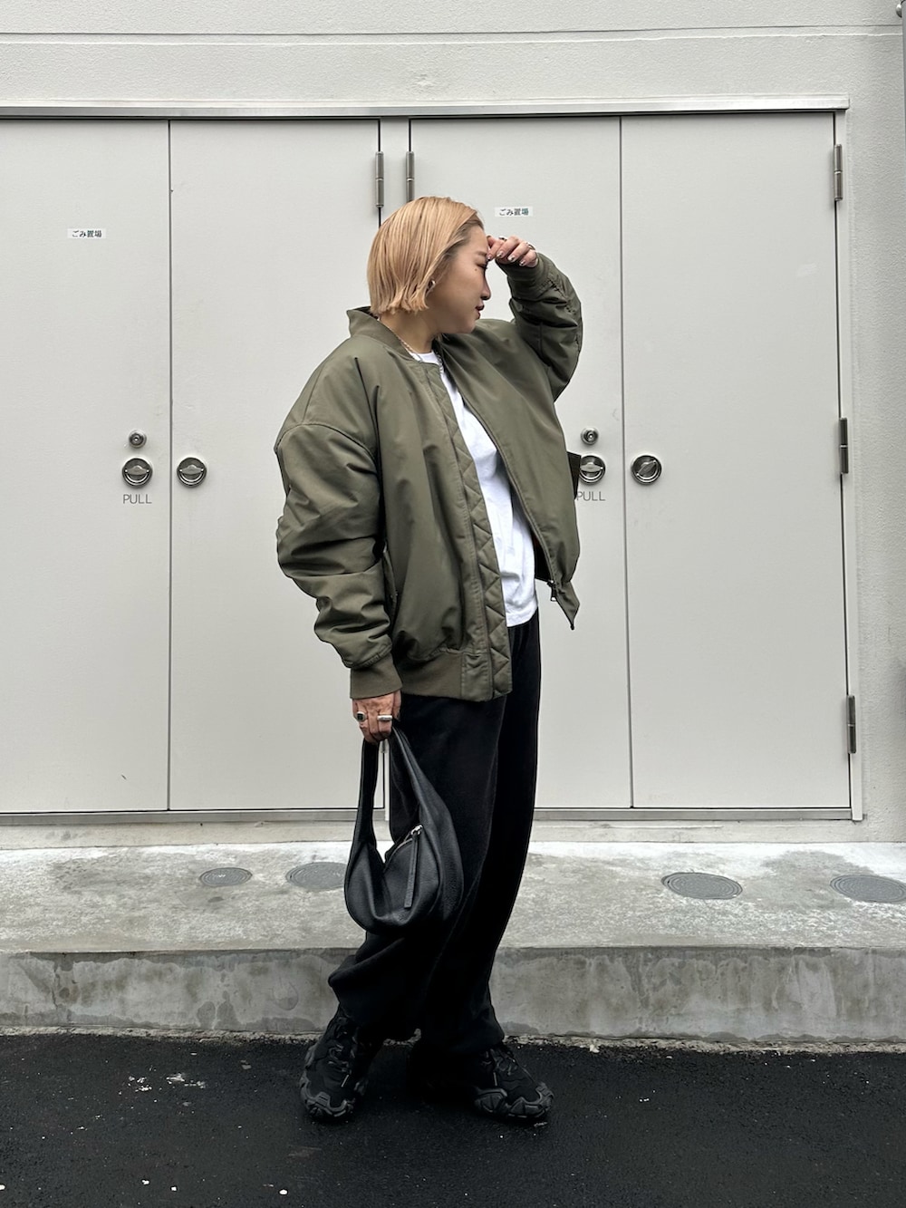 グリーン系のMA-1、ブラック系のハンドバッグ、ブラック系のスニーカーを着用したレディースの冬コーディネートの2枚目の写真